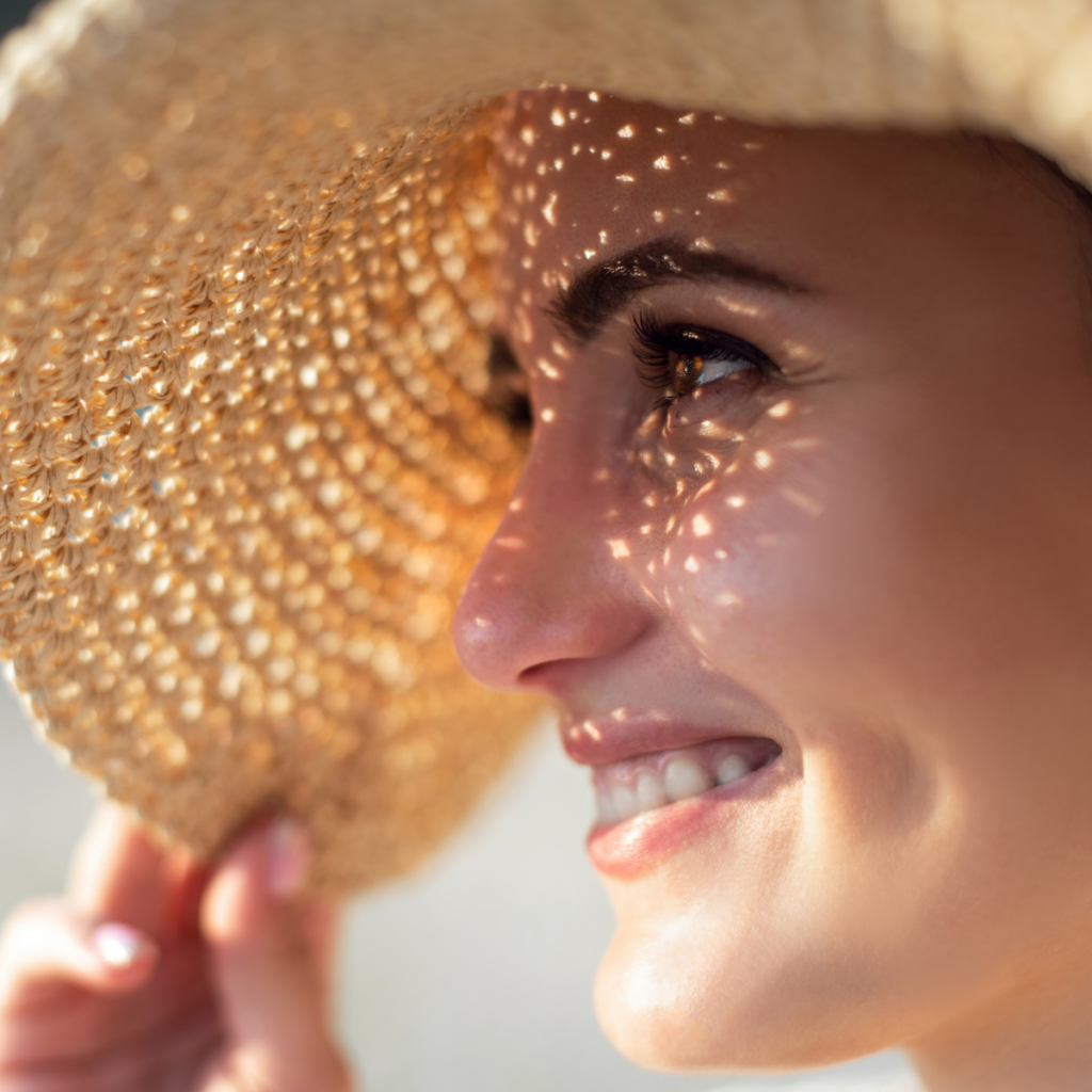 Aurinko ja iho ovat hyvä yhdistelmä, kun iho on oikein suojattu. Kuvassa nainen leveälierinen olkihattu päässä auringossa. 